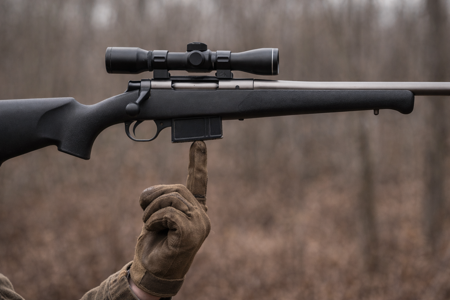 Hands balancing a lightweight deer rifle on one finger showing ideal balance point near magazine well